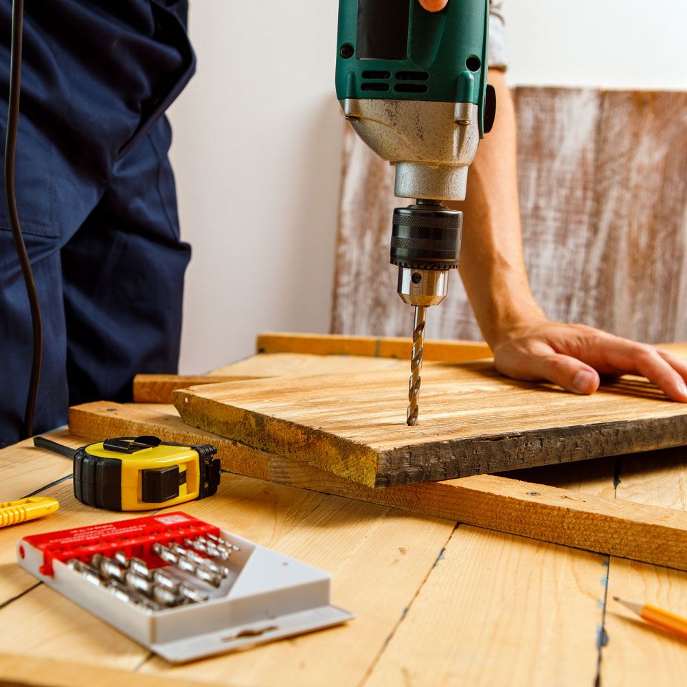 Professional carpenter drilling wood during home improvement construction work