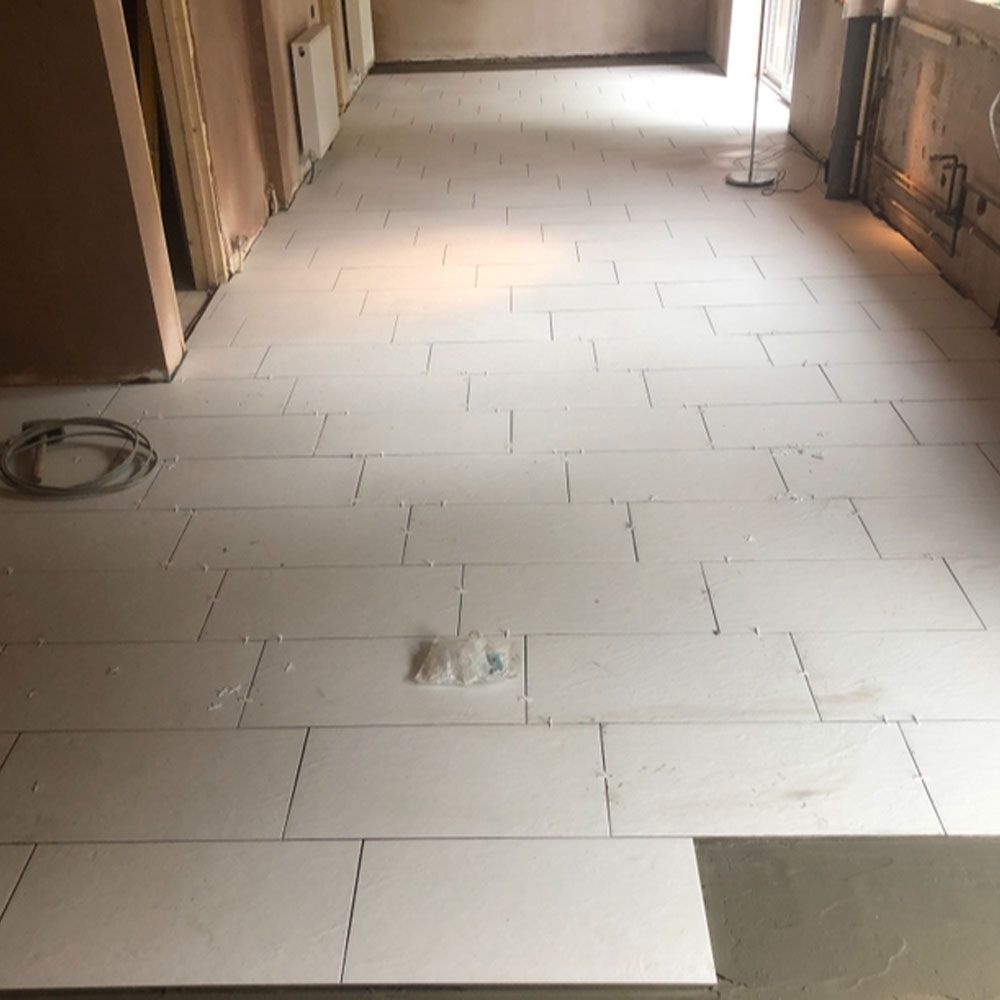 White tiles laid in residential hallway during home improvement flooring installation