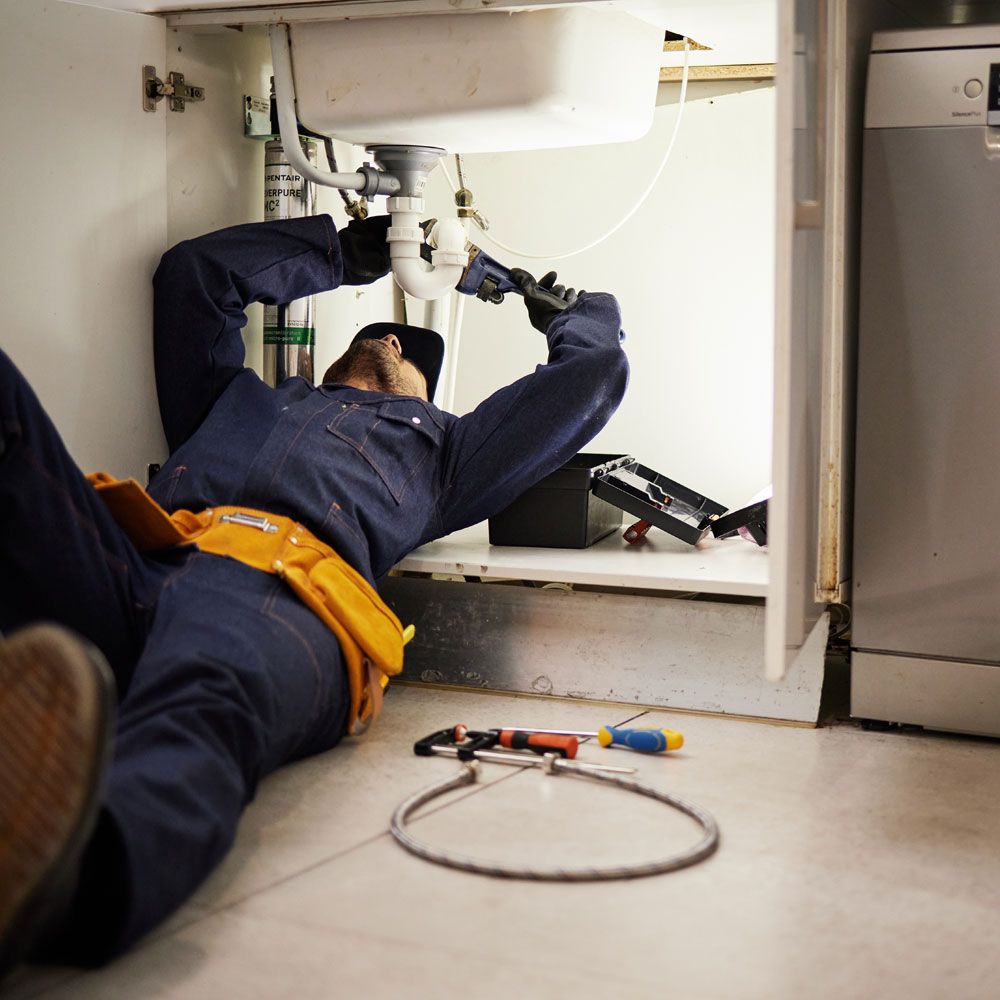 Professional plumber fixing water leak during home improvement in Solihull